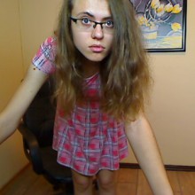 Pellyny standing in front of camera wearing glasses and red dress